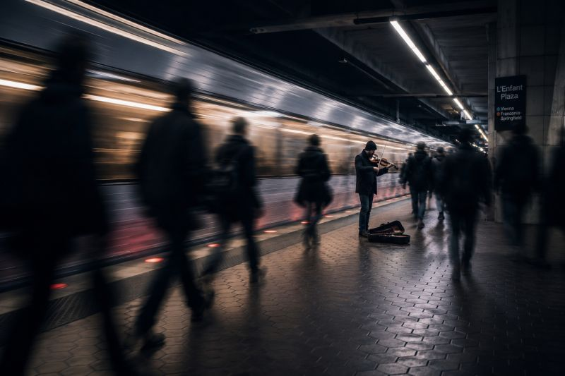 Un violinista toca en una estación mientras los viajeros pasan