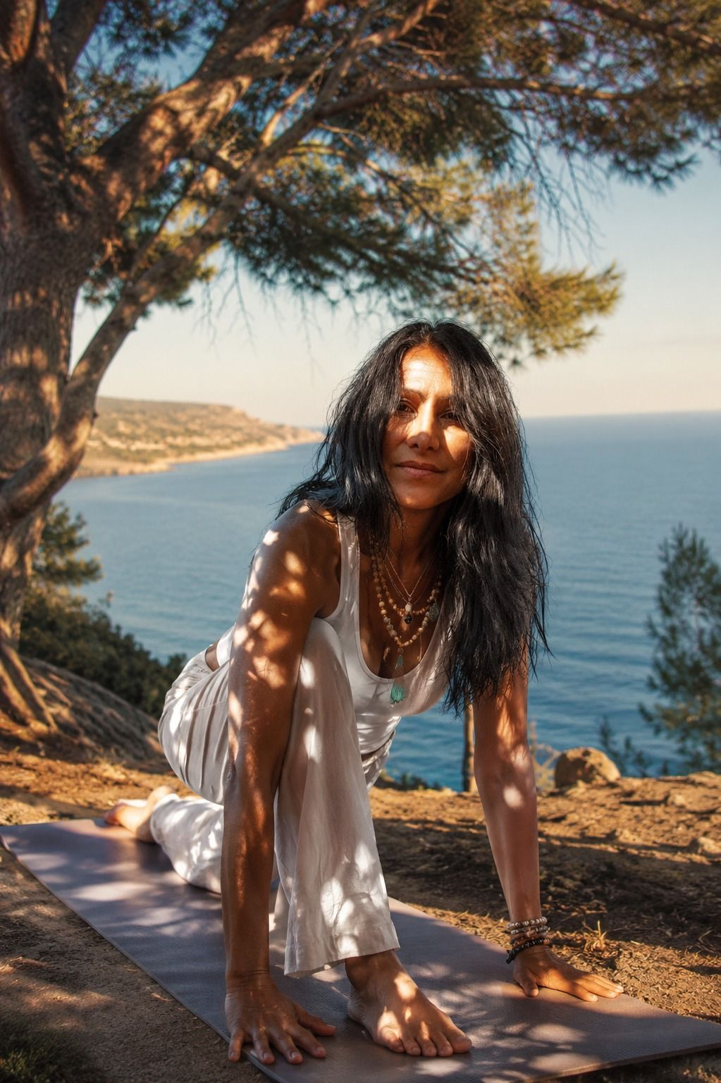 María Eugenia practicando yoga bajo un árbol frente al mar